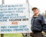 Jackie Vautour sur sa terre dans le parc national Kouchibouguac devant son affiche qu’il a installée à l’entrée du parc. Photo tirée du film Kouchibouguac : L’histoire de Jackie Vautour et des expropriés. &mdash; Bellefeuille Production