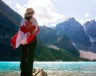 Une personne avec un drapeau canadien sur son dos, regardant le parc national Banff, qui est le plus fréquenté au Canada.   — Photo : @andre-furtado – Pexels