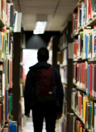 Un étudiant dans une bibliothèque. — PHOTO: Redd Francisco - Unsplash