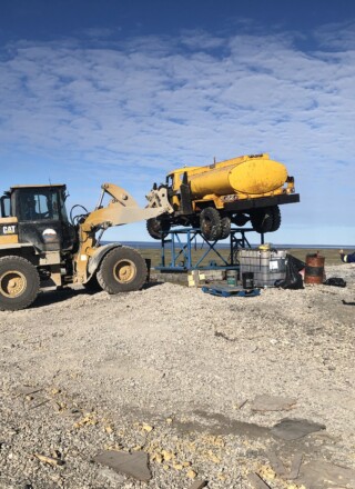À Ulukhaktok en juillet 2023, le personnel de KBL Environmental s’affaire à retirer de la décharge un camion-citerne.  &mdash; Courtoisie MAMC