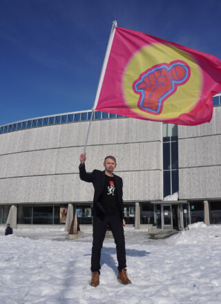 Amund Sjølie Sveen brandissant la bannière Pan-ArcticVision devant le centre culturel Katuaq à Nuuk lors du Pan-Arctic Vision 2024.  — Courtoisie Nordting