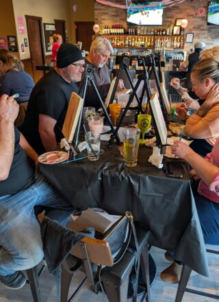 Groupe Franco albertain en pleine action - Peinture des portraits de leurs conjoints lors de la Saint valentin au Mr Mikes - Lacombe &mdash; Crédit : Courtoisie
