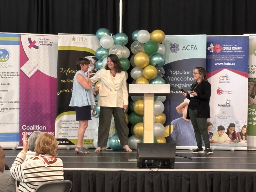 Mme Mireille Péloquin, directrice générale de l'Association des parents francophones de l'Alberta,  a gauche, recevant les hommages de ses collaboratrices à la fin du sommet : « On ne transmet pas seulement une langue, on transmet des humains. »
 &mdash; Crédit : Le Franco