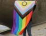  Une personne sous un pont tenant un drapeau de fierté inclusif, symbolisant la diversité.
 &mdash; Crédit : Pexels
