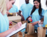Group of volunteers working with donate food, team leader checking list in clipboard, copy space  