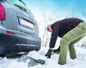 man digging up stuck in snow car  