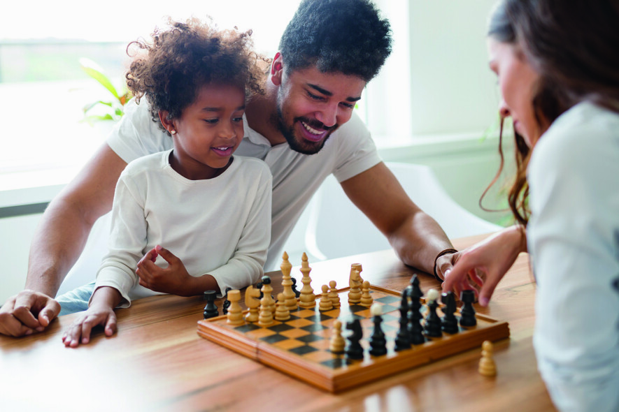 Happy family playing chess together at their home  