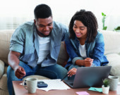 Young african spouses managing their family budget together at home, checking financial documentation  