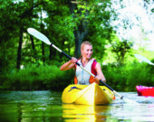 Woman paddling with canoe on forest river  