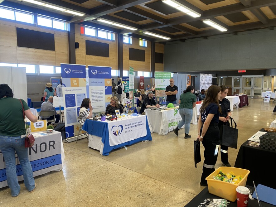 Des chercheurs d’emploi échangent avec des représentants d’entreprises locales lors de la foire d’emploi organisée au gymnase de l’Université de Hearst. &mdash; Photo : Ndery Dione