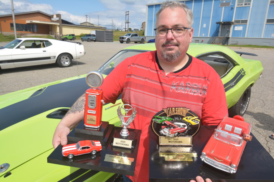 Yan Poirier prend la pose à côté de sa voiture de collection. Sur la couverture, le passionné d’automobiles exhibe fièrement les deux trophées qu’il a remportés lors de la deuxième édition du Motorama. — Éric Cyr (TDN)
