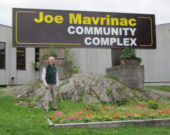 L’ancien maire Joe Mavrinac lors de l’installation de l’affiche à son nom devant le complexe sportif de Kirkland Lake. &mdash; Photo : Courtoisie