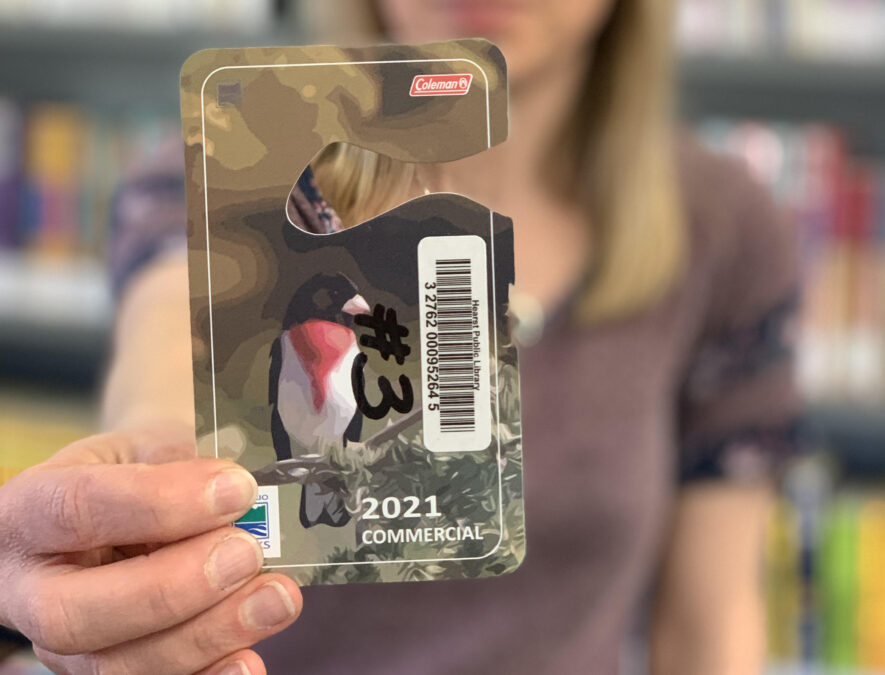 Julie Portelance, la nouvelle directrice de la bibliothèque publique de Hearst, montre l’une des passes commerciales qui permettent l’accès aux Parcs Ontario. — Photo : Chloé Vachon, bibliothèque de Hearst.