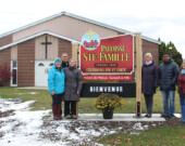 Une partie du groupe responsable de la paroisse et de la célébration autour de la nouvelle affiche devant l’église Ste-Famille. Nicole Meritt, le directeur de l’École secondaire catholique Jeunesse-Nord Hassan Azzi, la directrice de l’École Saint-Joseph Julie Chenard Azzi, Diane Bray, le curé Clarence Dinesh Narendra et Suzanne Kearns. Absents : Guy Chénard, Shirley Lemieux et Marguerite Déquanne.  &mdash; Photo : Julien Cayouette