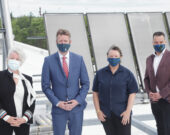 De gauche à droite : Annette Verschuren, membre du Conseil de croissance économique du premier ministre, le premier ministre Iain Rankin, Beth Mason, PDG du Verschuren Centre, et l’honorable Derek Mombourquette, ministre de l’Éducation et du Développement de la petite enfance, posent devant des panneaux solaires et un parc éolien situé à proximité, sur le toit du Verschuren Centre, sur le campus de l’Université du Cap-Breton.   &mdash; Communications Nova Scotia