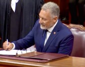Le sénateur Allister Surette, qui est en train de signer le registre du Sénat, lors de la cérémonie d'assermentation. &mdash; PHOTO: Capture d’écran - Parlement du Canada