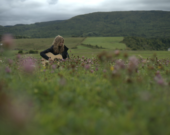 Adèle Deveaux joue de la guitare, dans un champ de fleurs sauvages.  &mdash; PHOTO: Robert Mentov / KAPSUR, TFO