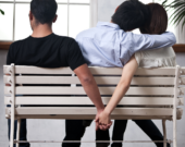Une femme tient la main à un autre homme dans le dos de son amoureux.  