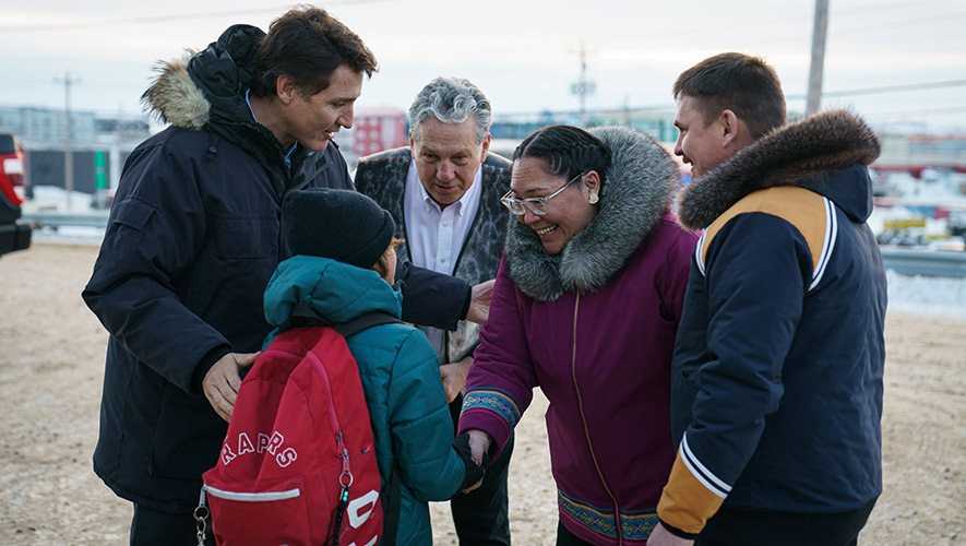 Justin Trudeau, Dan Vandal, Aluki Kotierk et P.J. Akeeagok avec un enfant. Ce transfert des responsabilités permettra de créer des emplois, des possibilités et des investissements dans le Nord et d’accroître la prospérité du Nunavut et de ses habitants pour les générations à venir. &mdash; Photo : Adam Scotti – Bureau des Affaires du Nord