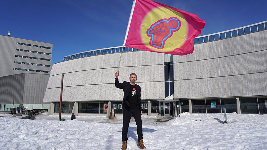 Amund Sjølie Sveen brandissant la bannière Pan-Arctic Vision devant le Centre culturel Katuaq à Nuuk lors du Pan-Arctic Vision 2024. &mdash; Photo : Nordting