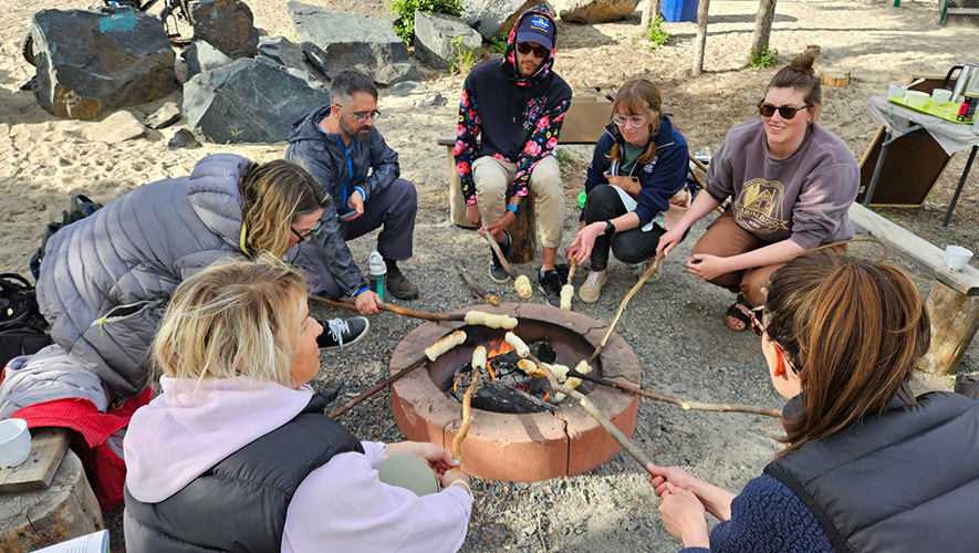 Des étudiantes et des étudiants du Collège Nordique en train de faire du bannock lors d’un cours de tłı̨chǫ yatıı̀ en pleine nature.  &mdash; Photo : Collège Nordique