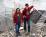 Sophie McGuinness, technicienne des systèmes d’informations géographiques, et Gillian Rourke, coordinatrice des ressources renouvelables et du projet, devant l’appareil sonar et un barrage en aluminium. &mdash; Photo : Sylvie Binette